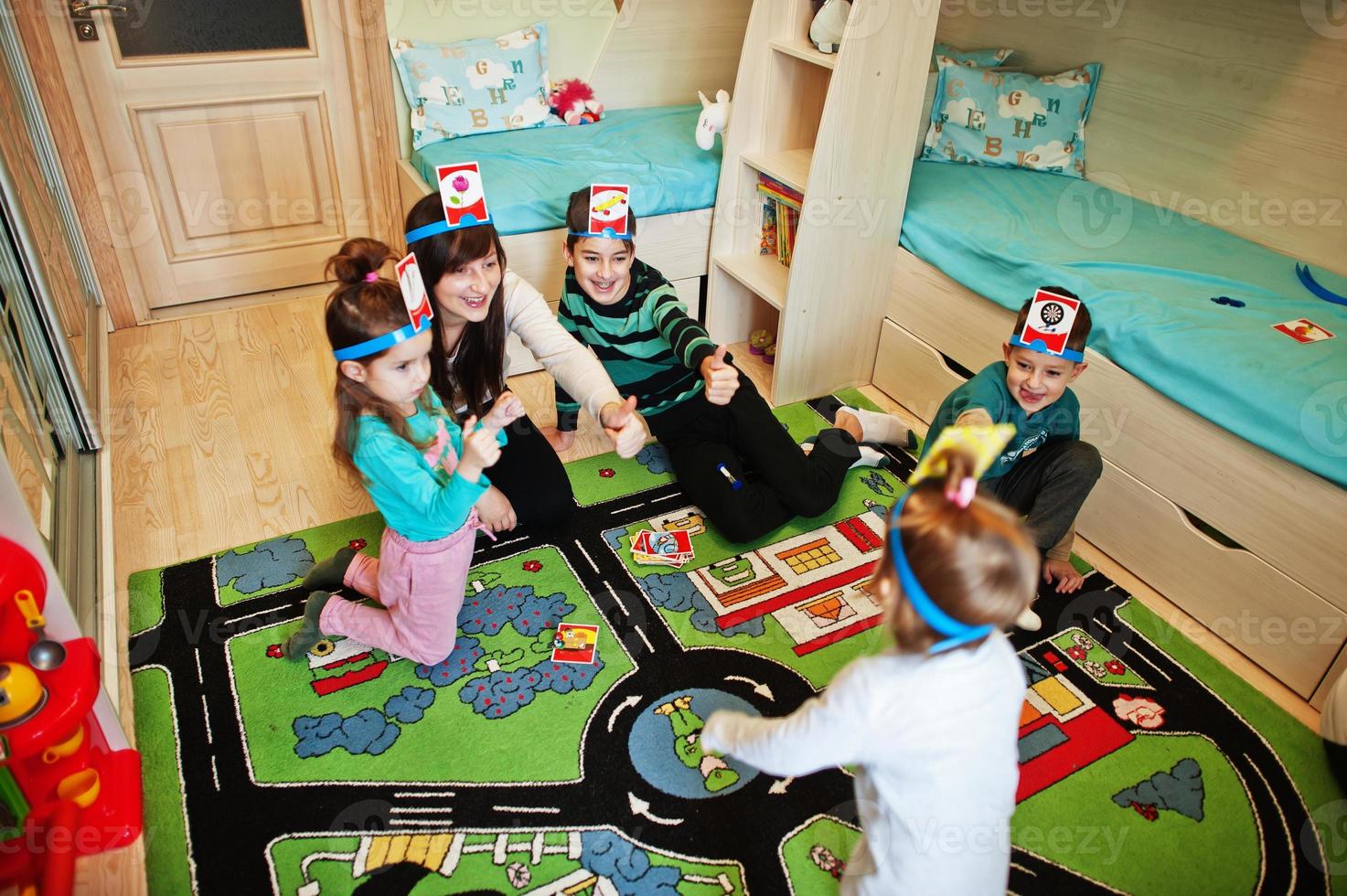 Happy family with four kids playing game guess who while having fun at home. photo