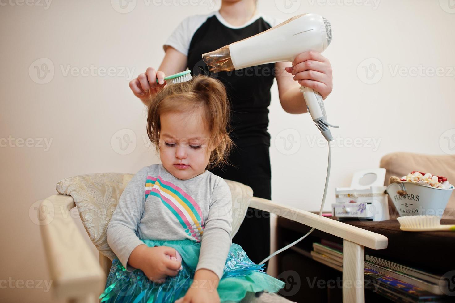 mamá con hija haciendo juntos la rutina diaria. la madre está cepillando y secando el cabello del niño después de la ducha. foto