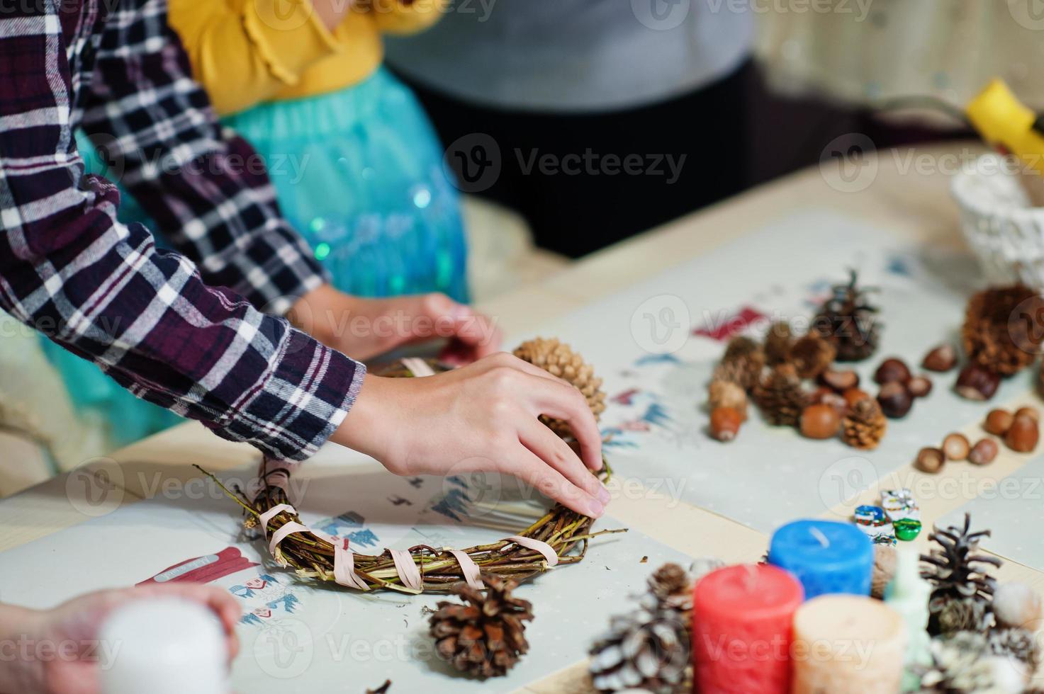 Hands of mother and kids makes a wreath for Christmas Eve and crafting decorating. New Year celebration. photo