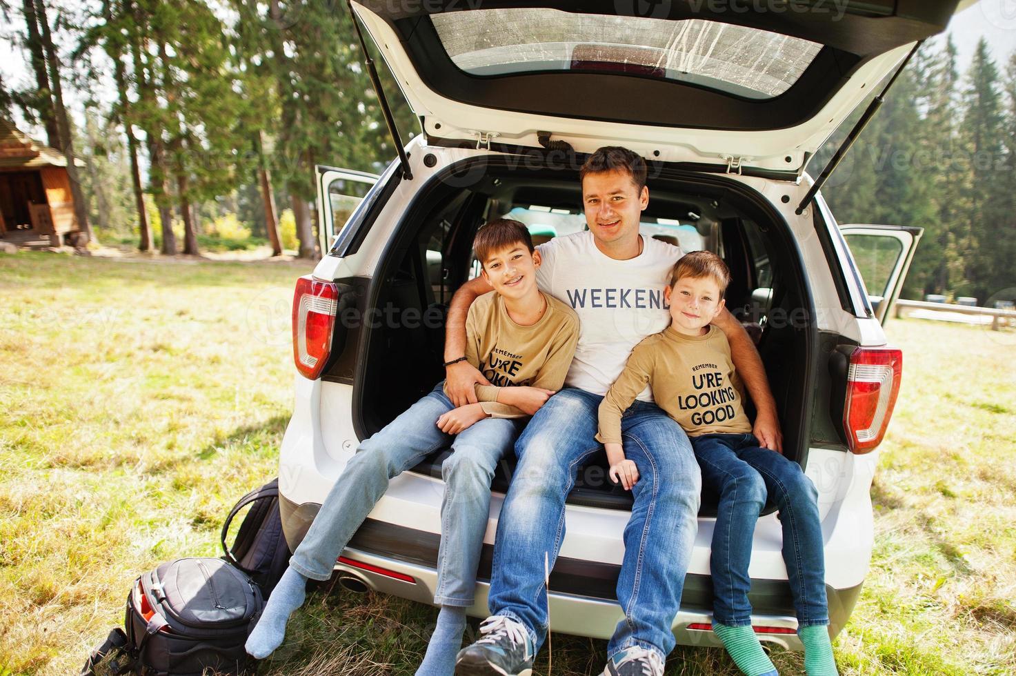 Family at vehicle interior. Father with his sons. Children in trunk. Traveling by car in the mountains, atmosphere concept. photo