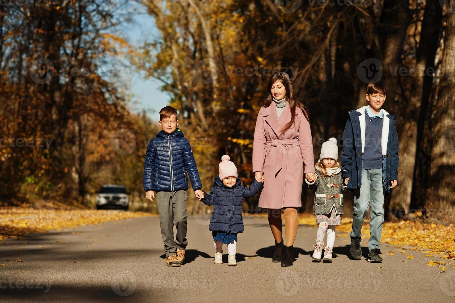 Mother with four kids in autumn park. Family walk in fall forest. photo