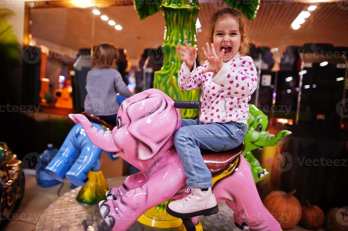 Two sisters rides an elephant carousel in fun children center. photo