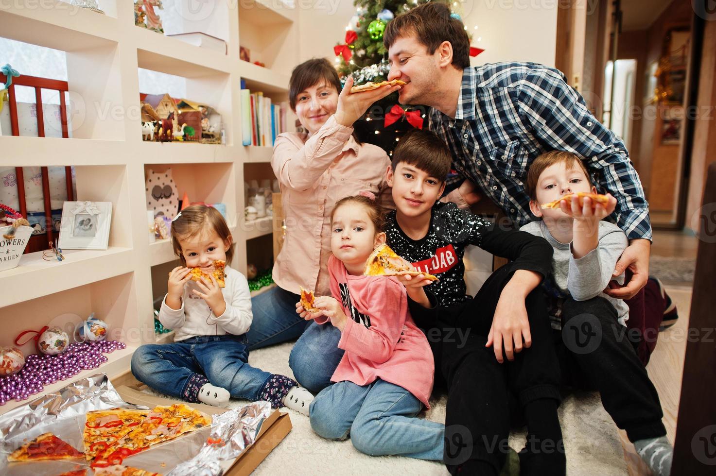 Happy family with four kids eating pizza at home. photo