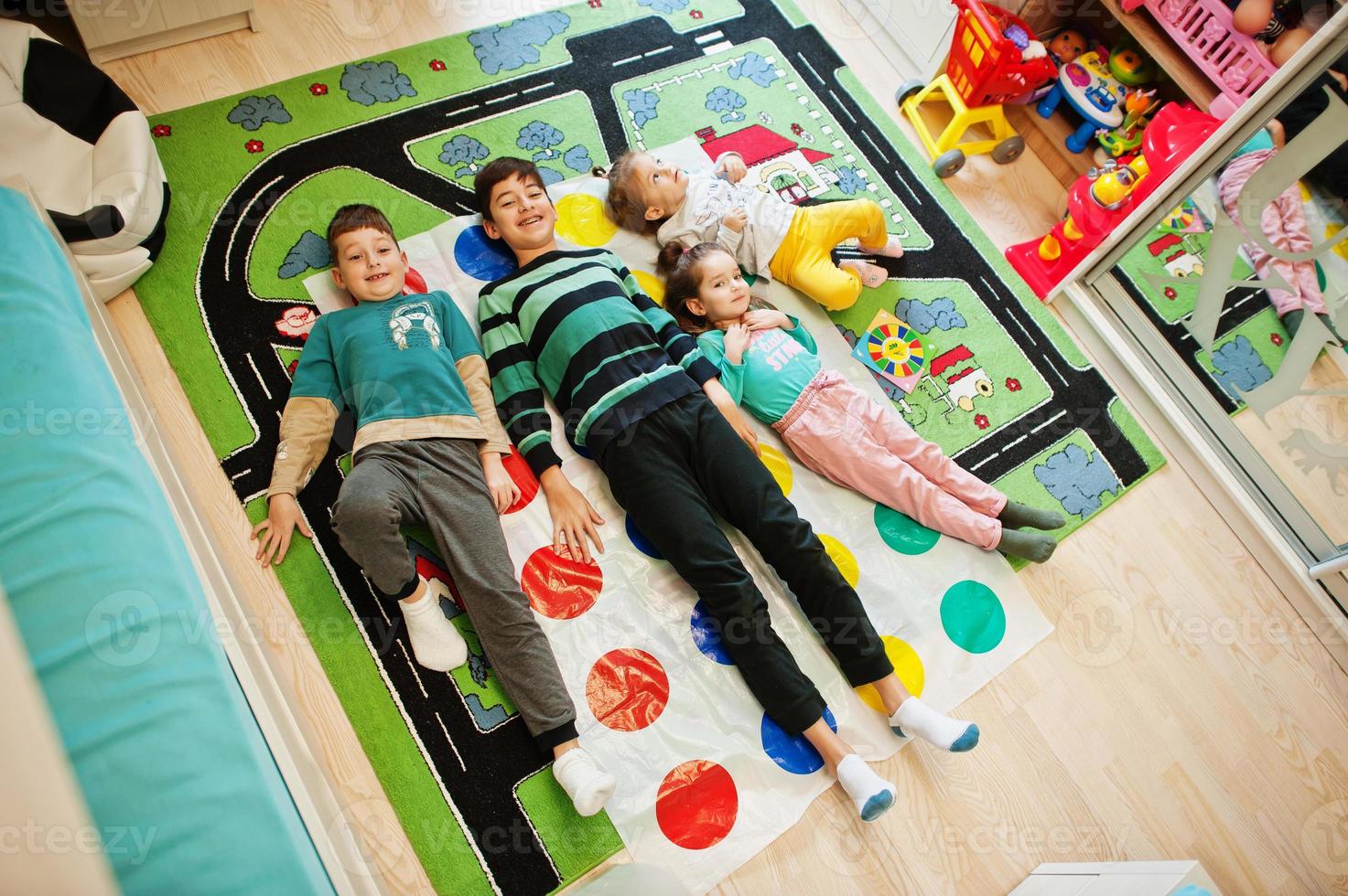 Happy family having fun together,four kids playing twister game at home. photo