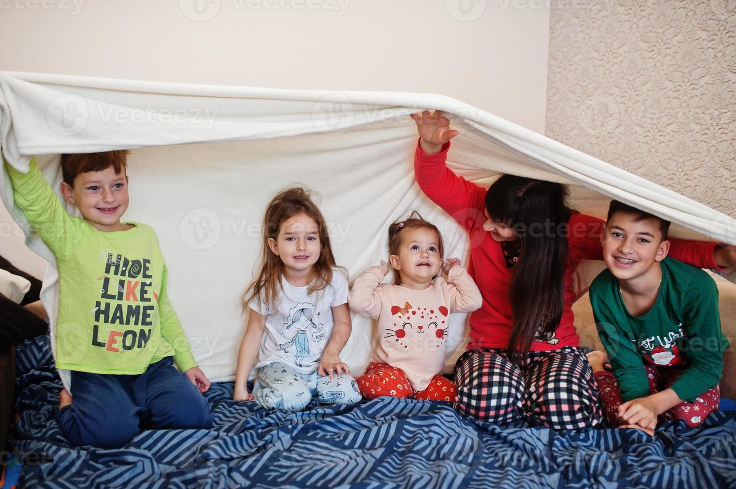 Happy big family is having fun together in bedroom. Large family morning concept. Mother with four kids wear pajamas in bed at home. photo