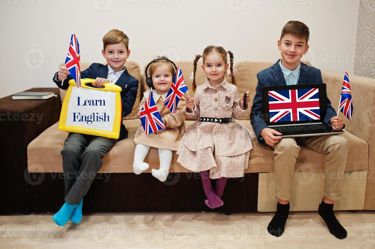 cuatro niños muestran inscripción aprender inglés. concepto de aprendizaje de idiomas extranjeros. foto