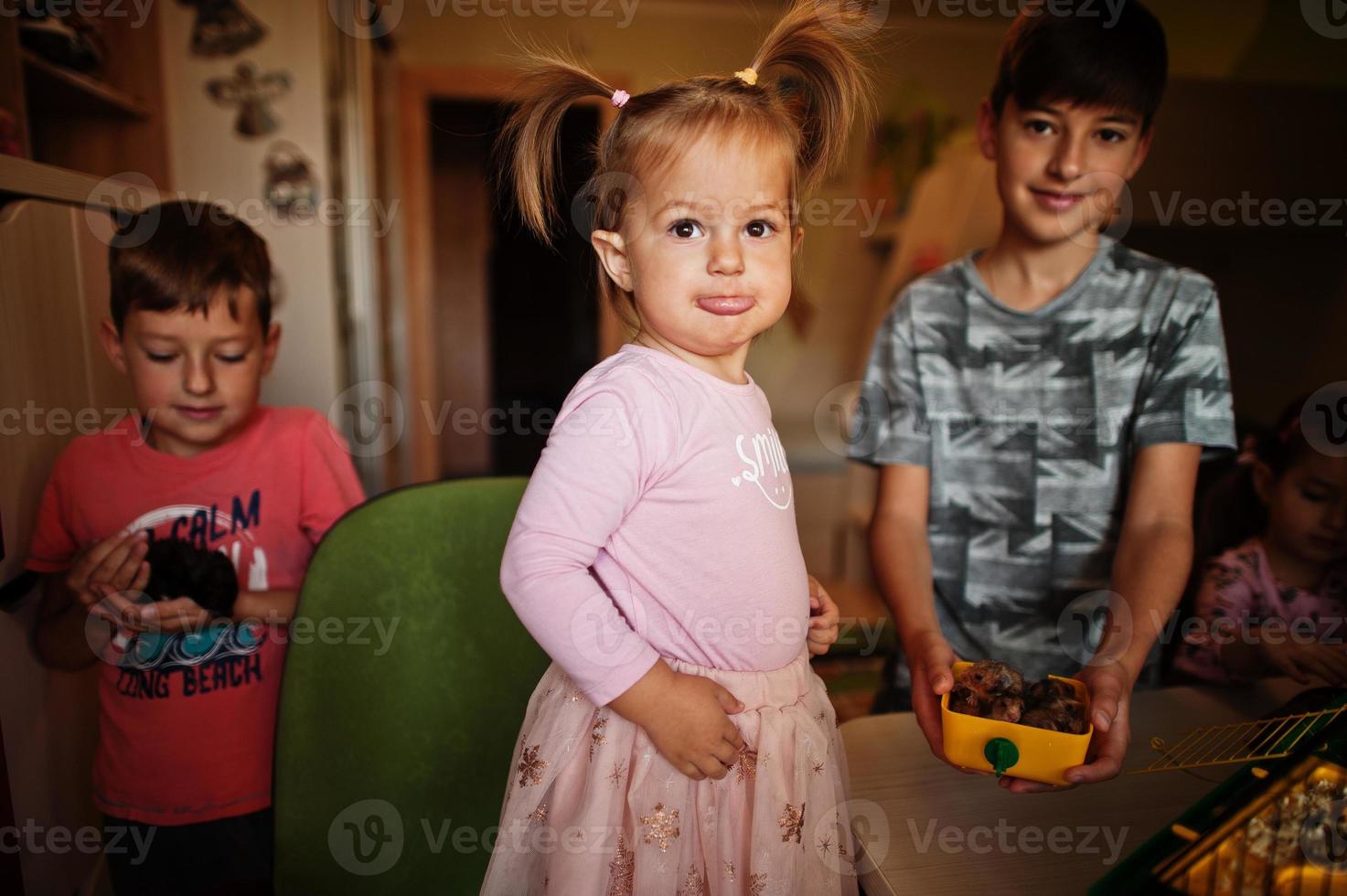 Four children holding their favorite pets on hands. Kids playing with hamster,turtle and parrots at home. photo