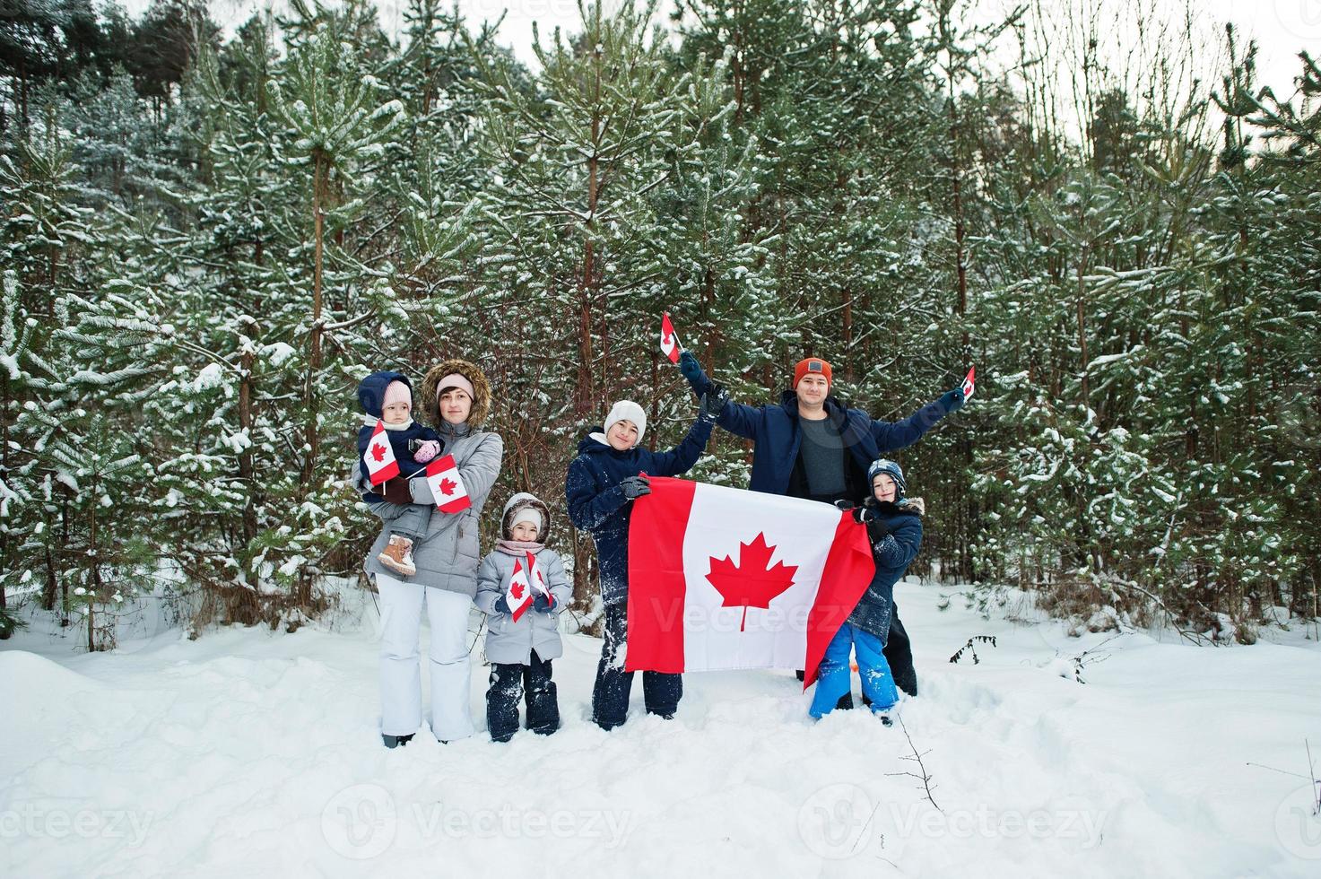 familia sosteniendo la bandera de canadá en el paisaje invernal. foto