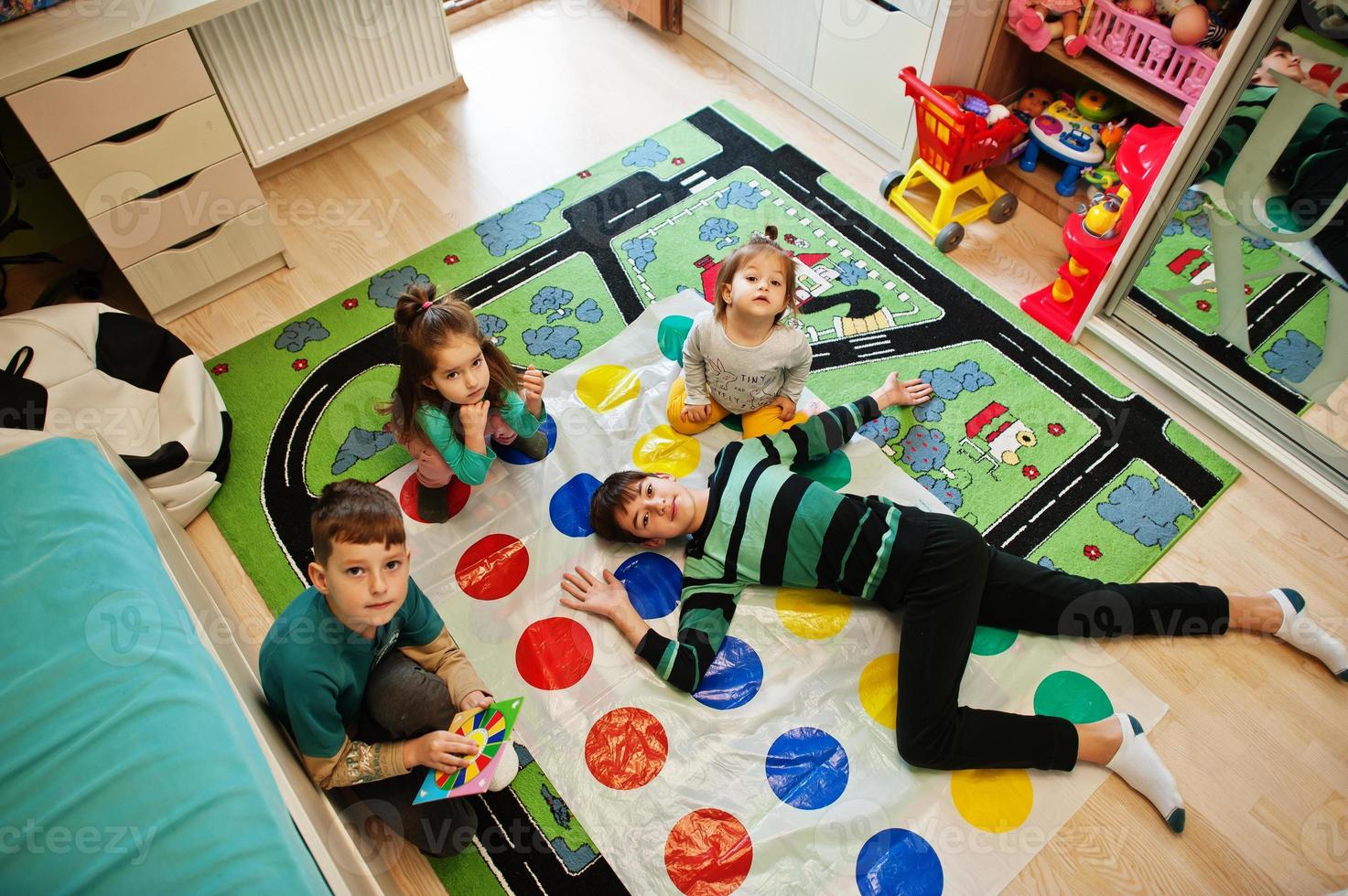 Happy family having fun together,four kids playing twister game at home. photo