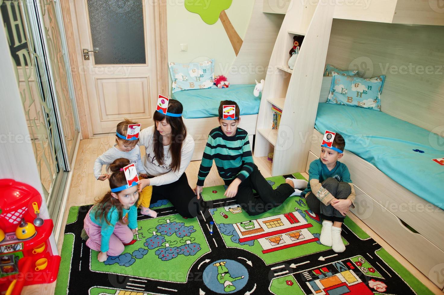 Happy family with four kids playing game guess who while having fun at home. photo