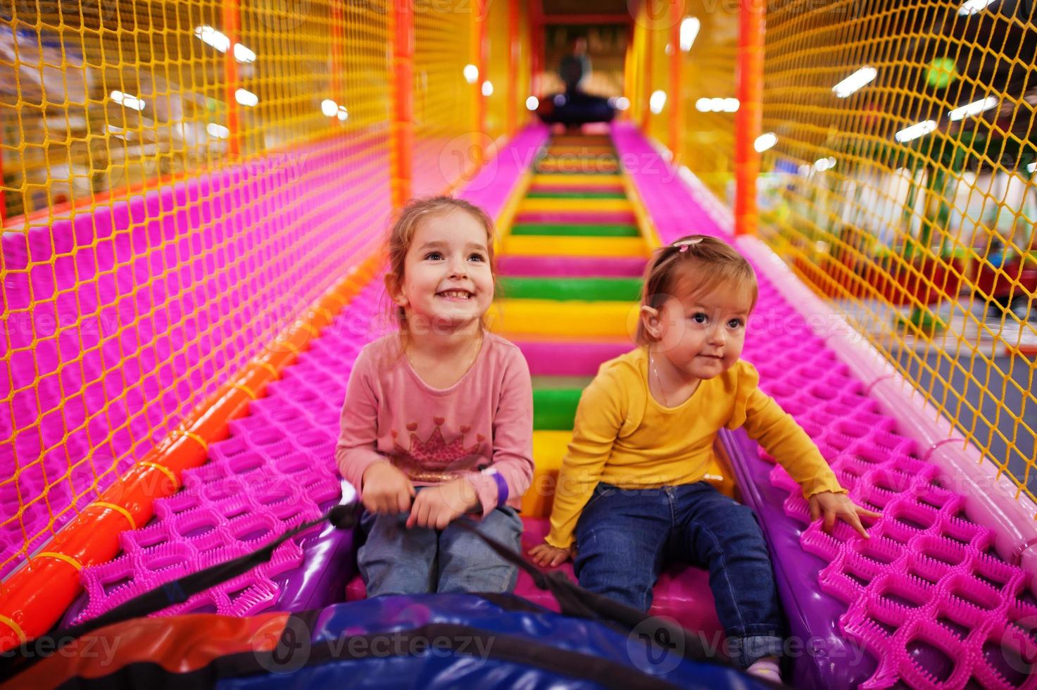 Two sisters sitting in tubing donuts enjoying slides in fun children center. photo