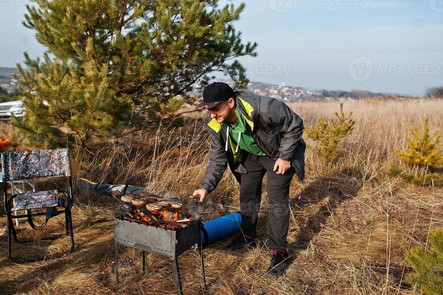 Man barbecuing on a deck in the pine forest. Bbq day with grill. photo