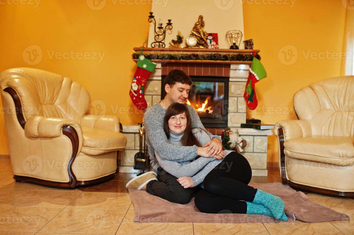 Happy young couple at home by a fireplace in warm living room on winter day. photo