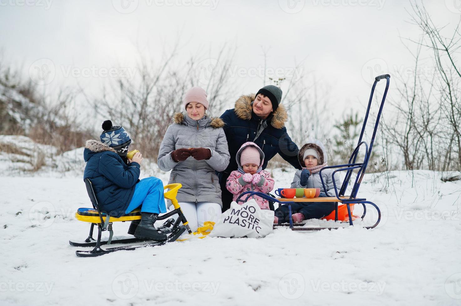 Family plays and sleigh rides in winter outdoor, children having fun, drinking tea. photo