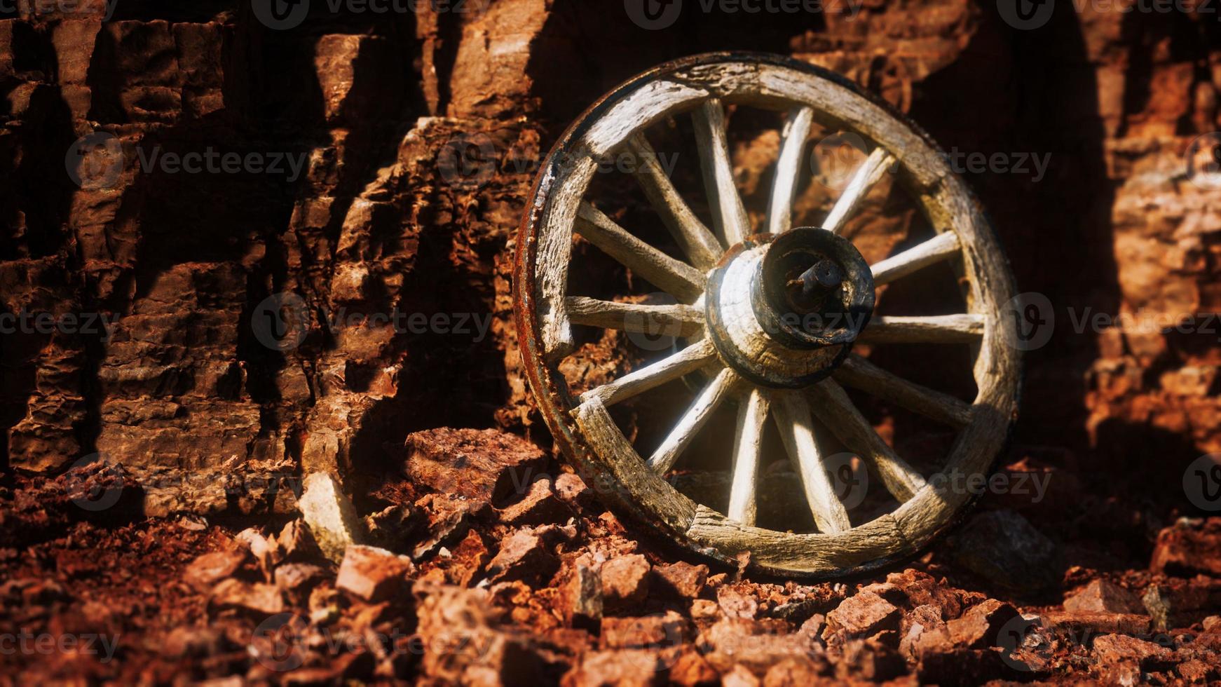 old wooden cart wheel on stone rocks photo