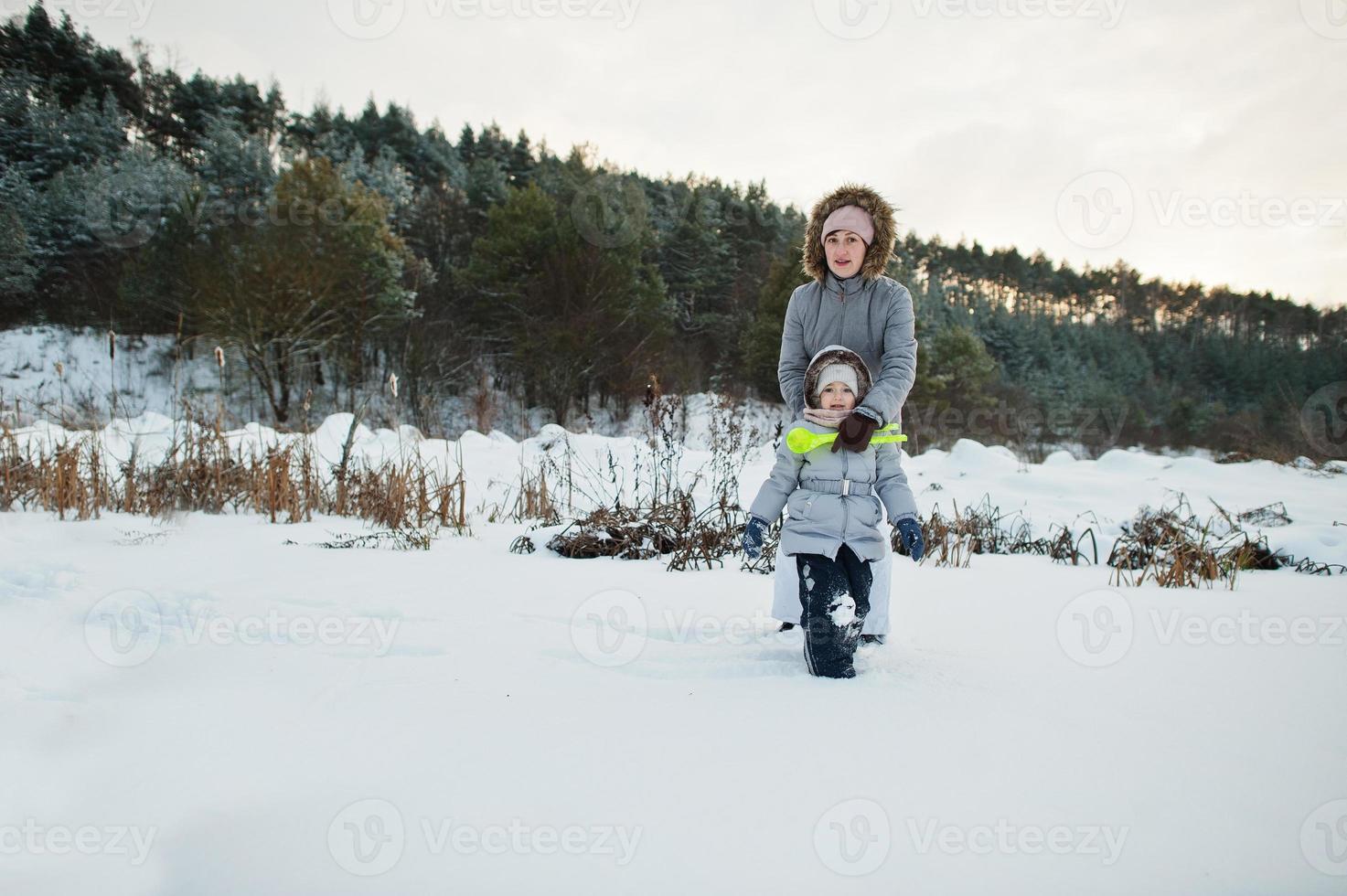 Mother with baby girl daughter in winter nature. Outdoors in snow. photo