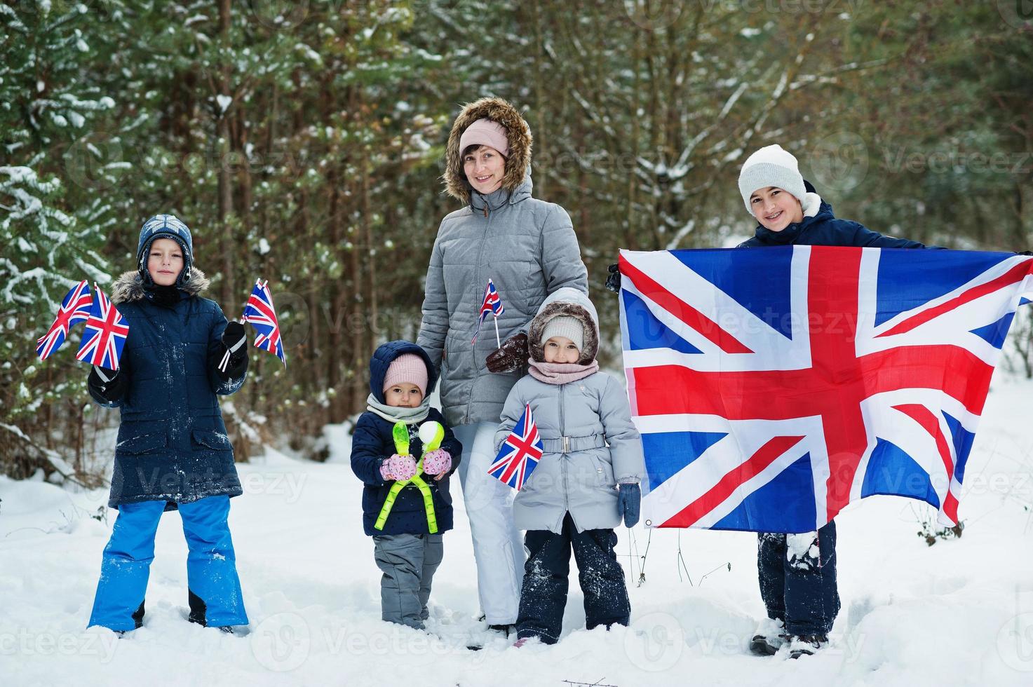 Mother with kids holding flag of Great Britain on winter landscape. photo