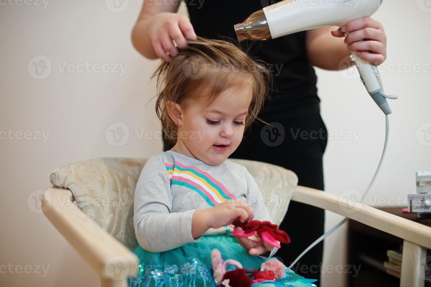 mamá con hija haciendo juntos la rutina diaria. la madre está cepillando y secando el cabello del niño después de la ducha. foto