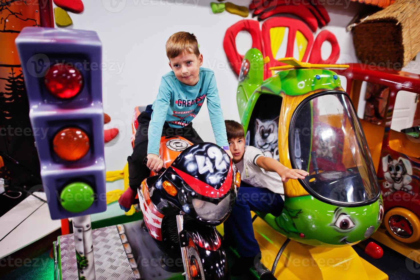 Two brothers sitting on motorbike and helicopter attraction in playground. photo