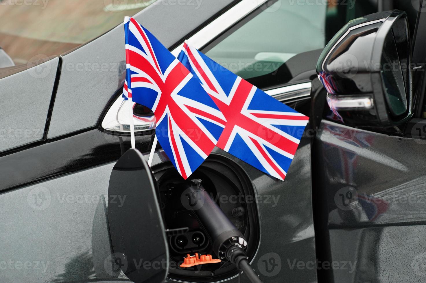 Great Britain flag ecological car concept. Plugging a power supplier, charging modern automobile. photo
