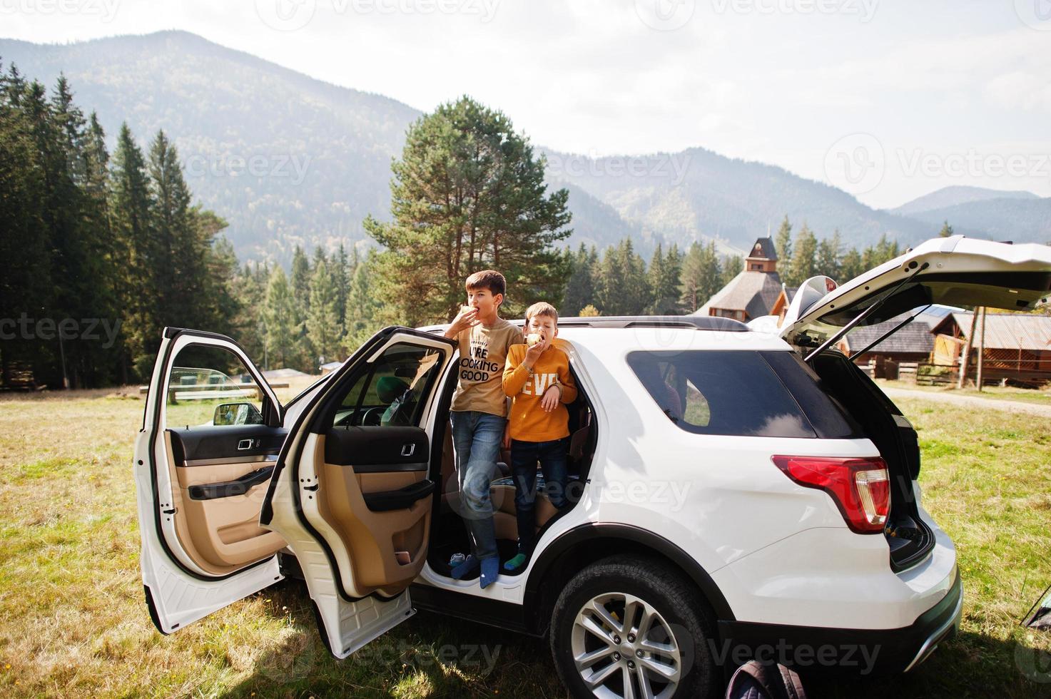 Two brothers eat apples at vehicle interior. Traveling by car in the mountains, atmosphere concept. photo