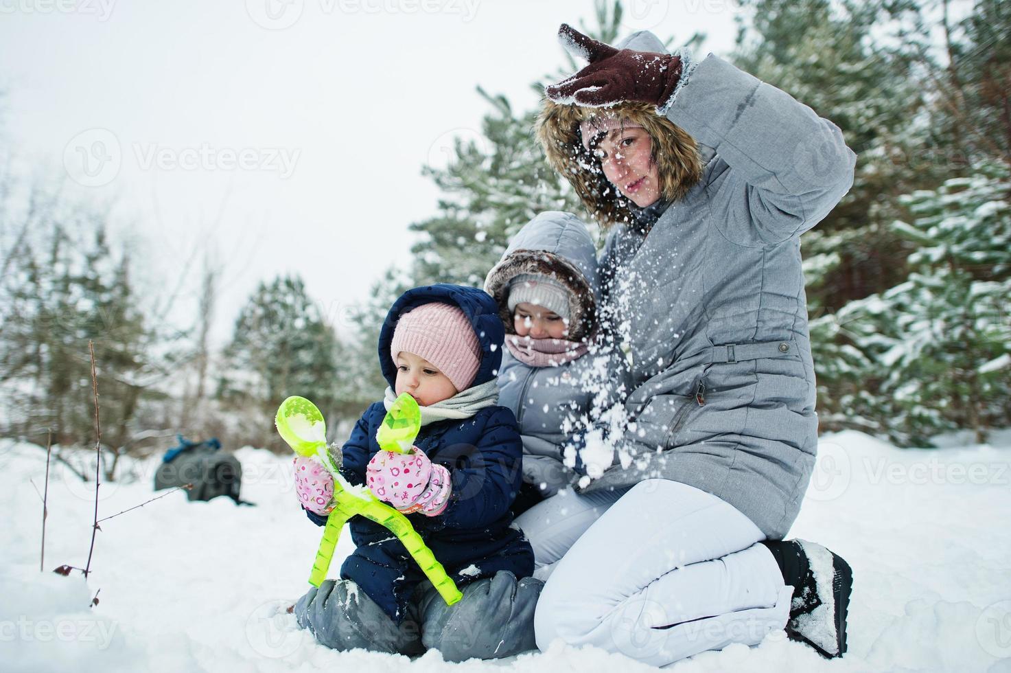 Mother with two baby girl daughters in winter nature. Outdoors in snow. photo