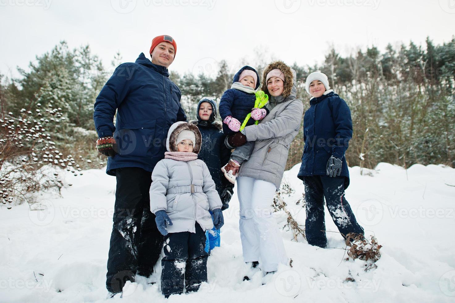 Father and mother with four children in winter nature. Outdoors in snow. photo