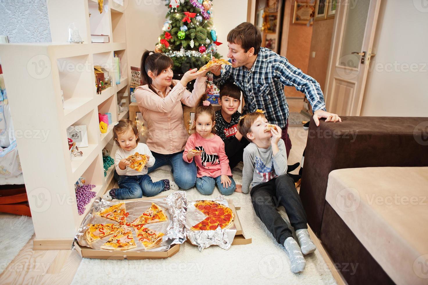 Happy family with four kids eating pizza at home. photo