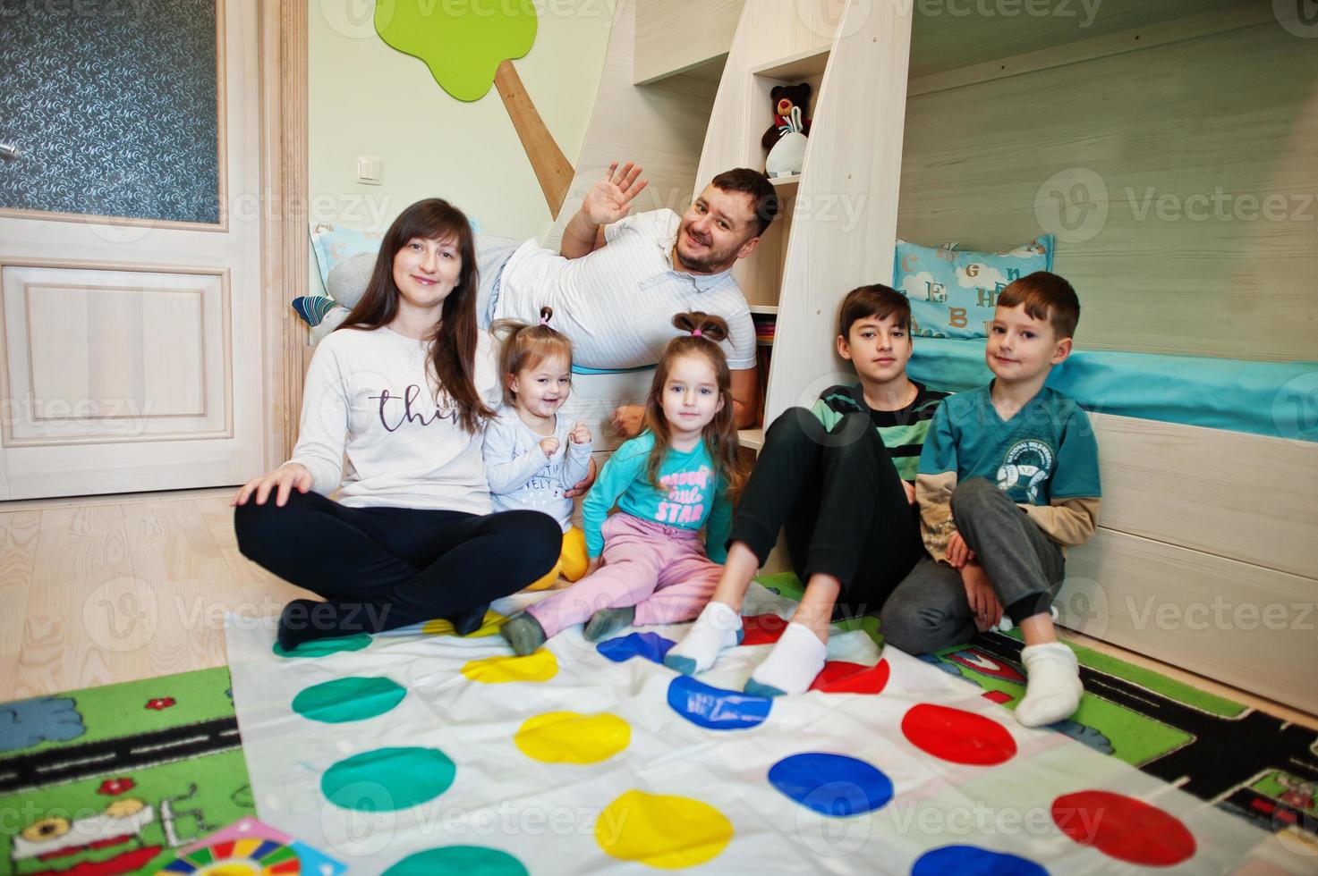 gran familia feliz divirtiéndose juntos, cuatro niños jugando al juego de tornado en casa. foto