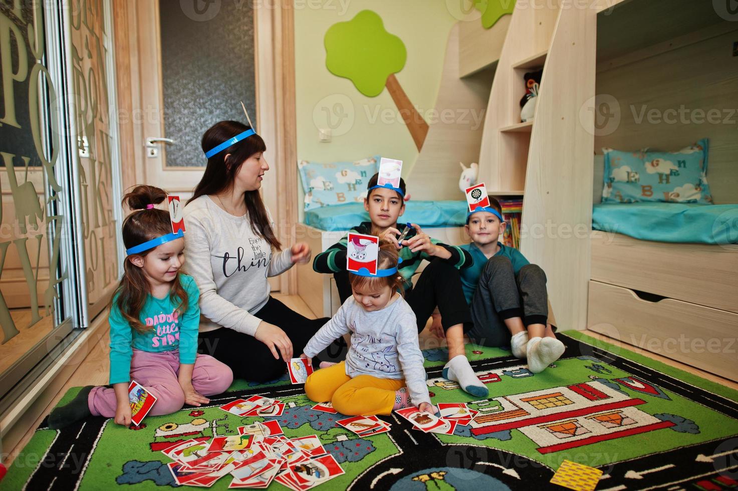 Happy family with four kids playing game guess who while having fun at home. photo