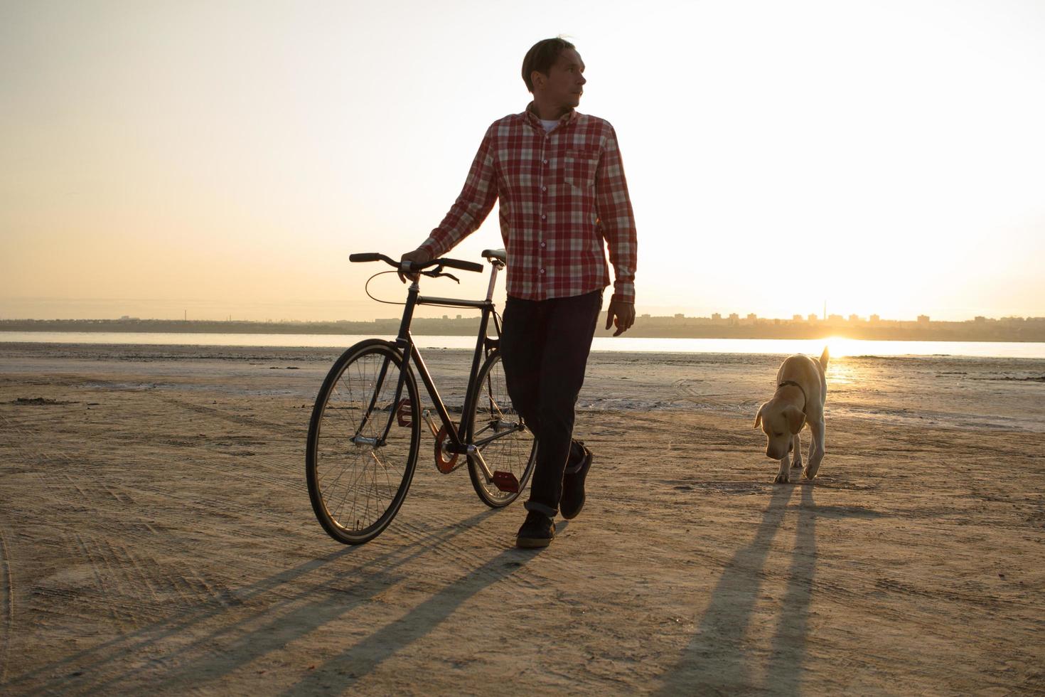 bicycle rider walking with retro black bike during sunrise at the desert photo