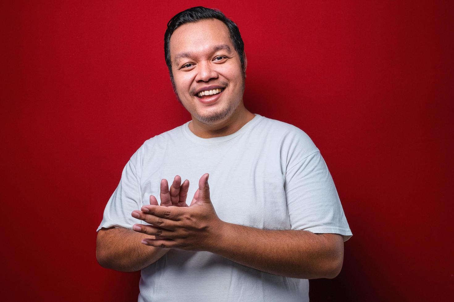 joven apuesto hombre vestido con una camiseta blanca aplaudiendo y aplaudiendo felices y alegres, sonriendo orgullosas manos juntas foto