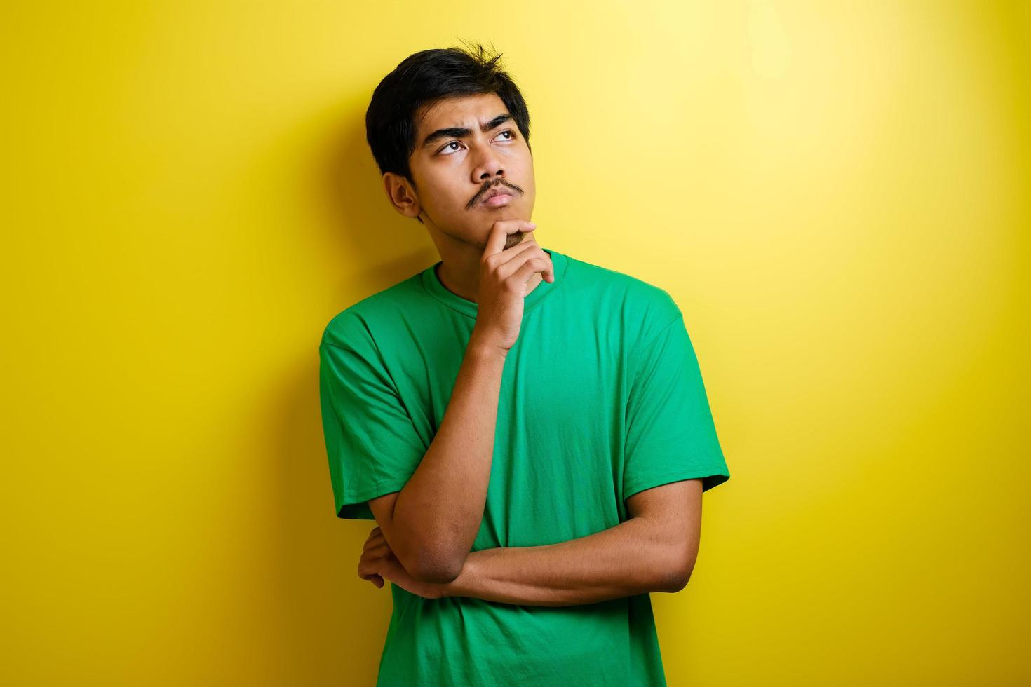 Asian man in green t-shirt thinking something, looking for good idea photo