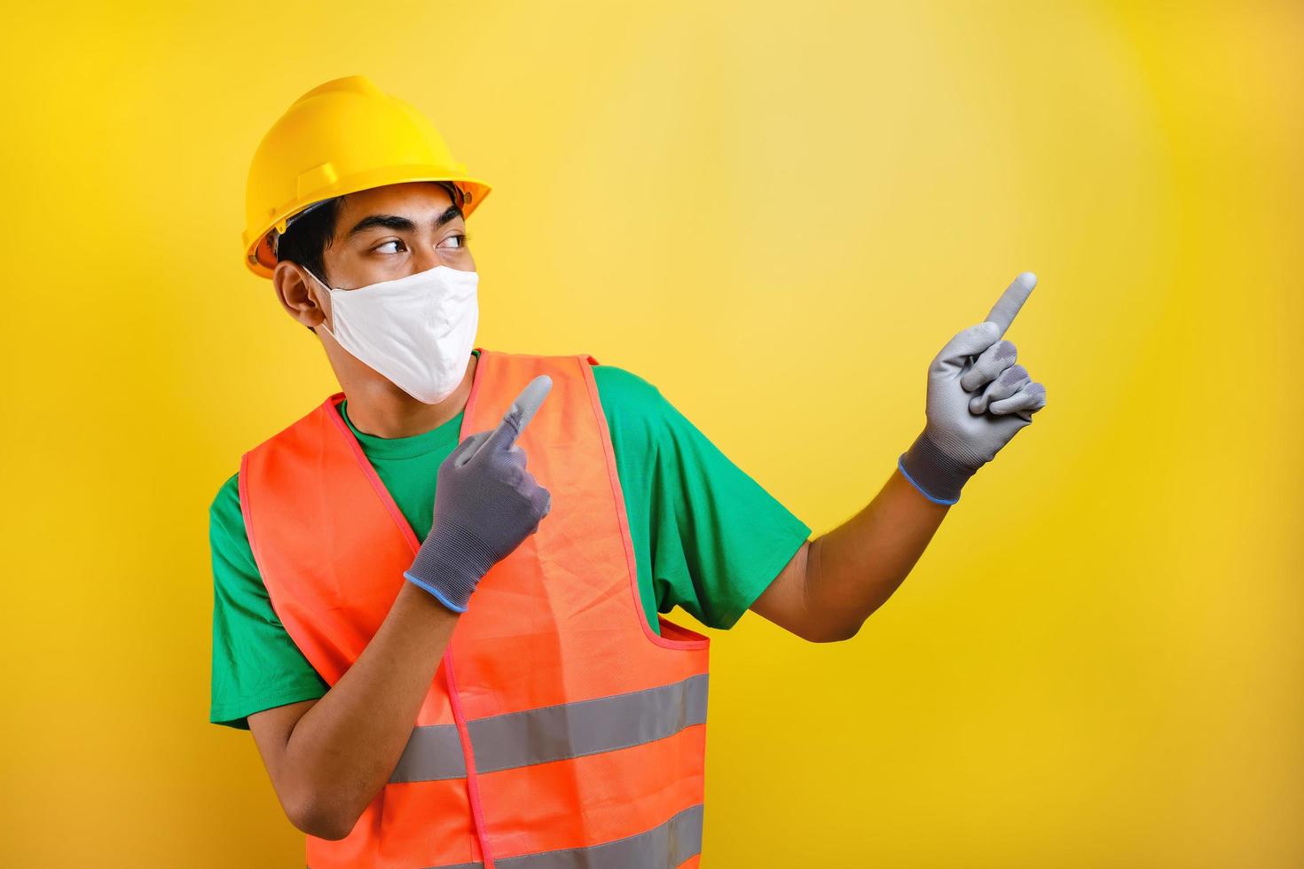 trabajador de la construcción asiático con máscara protectora que señala algo en su costado foto