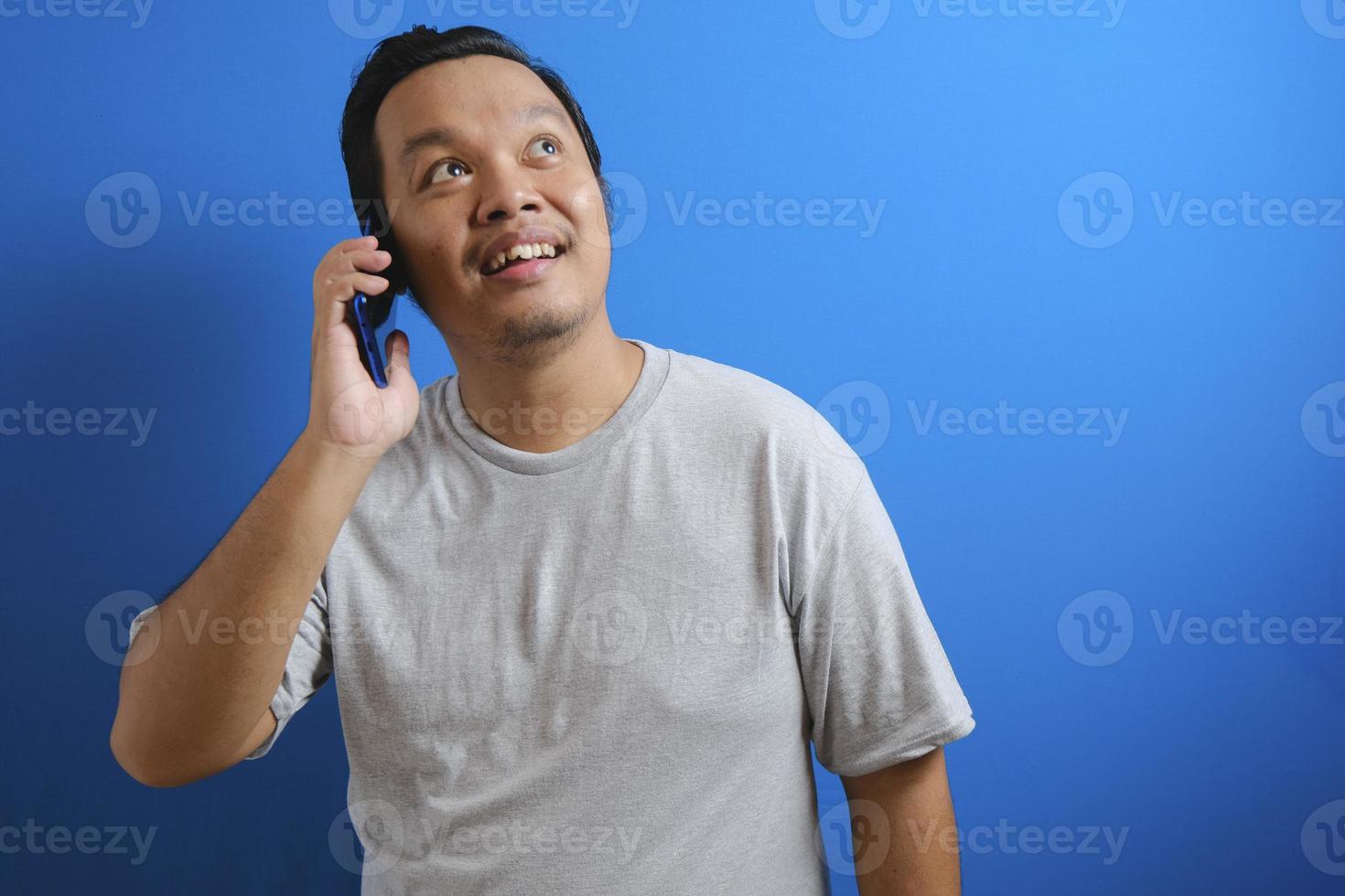 photo of a fat asian man wearing a gray shirt smiling while receiving a phone