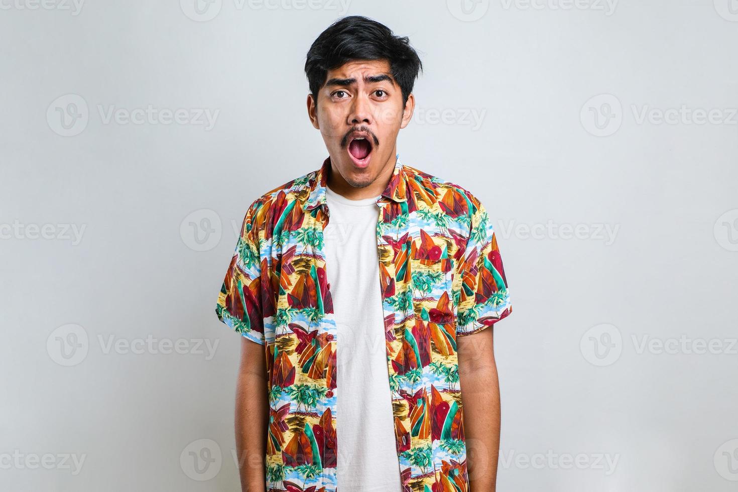 Amazed asian young man with open mouth and bulging eyes looking at camera photo