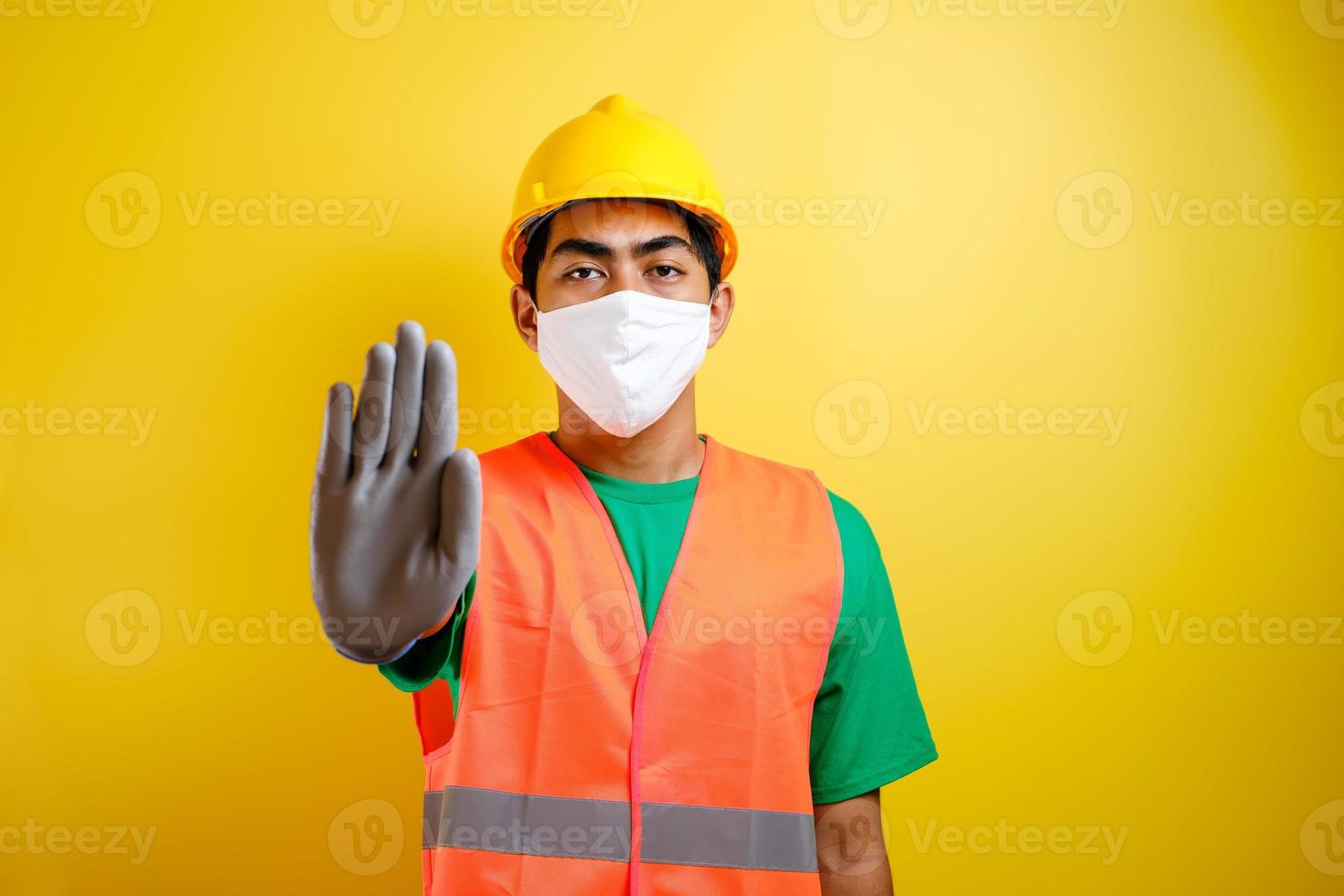 Asian construction worker wearing protective mask making stop gesture photo