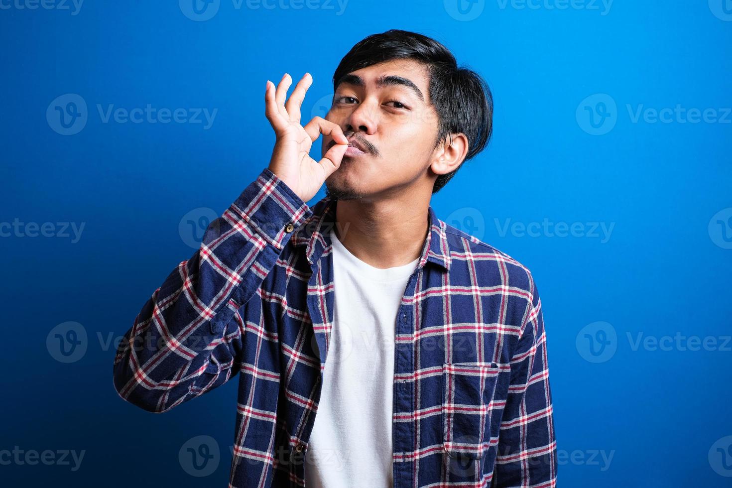 Happy asian man smiles looked at camera against blue background photo