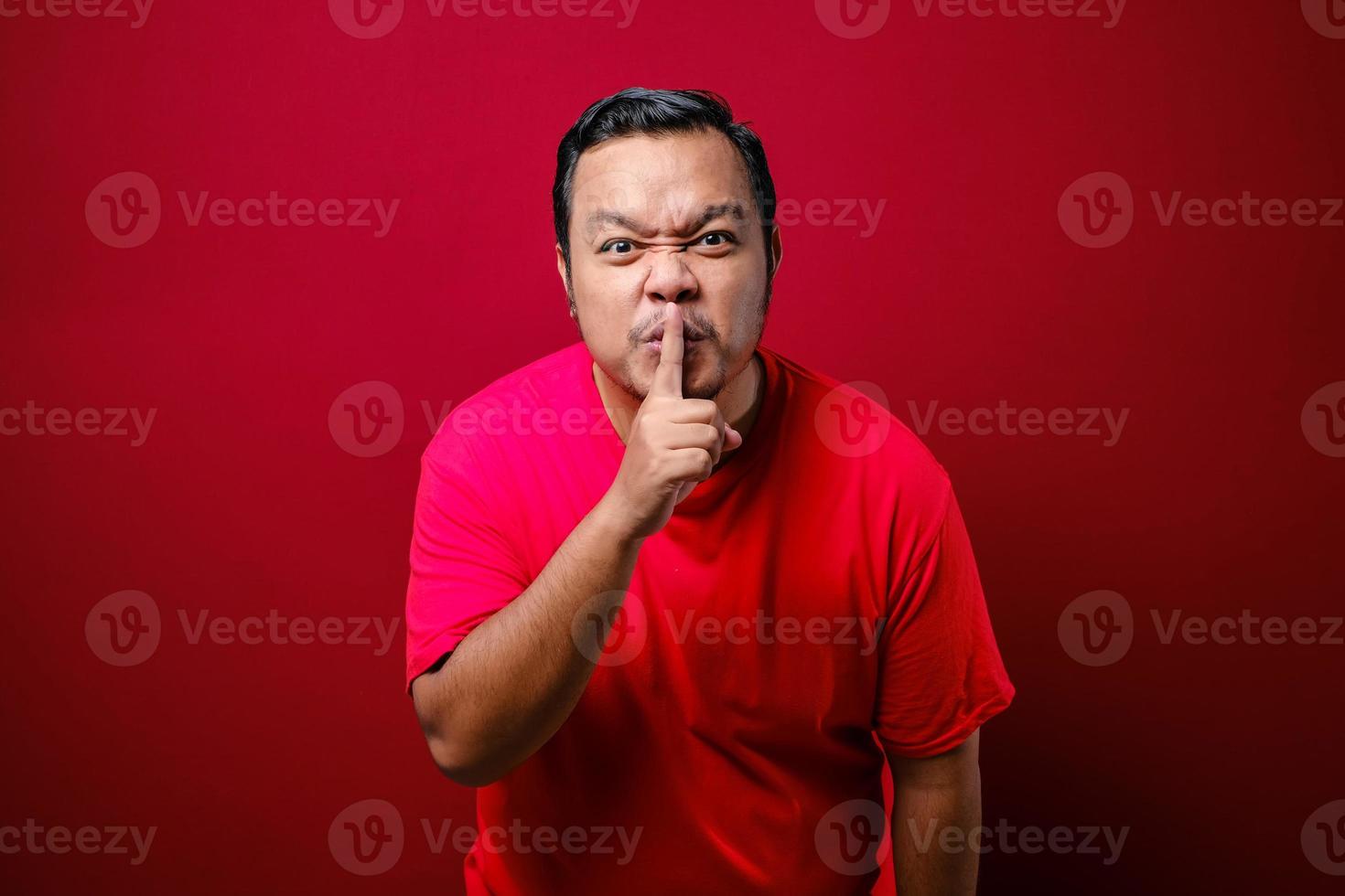 hombre serio y estricto sosteniendo el dedo cerca de los labios, mostrando un gesto shh pidiendo guardar silencio y ser bastante foto