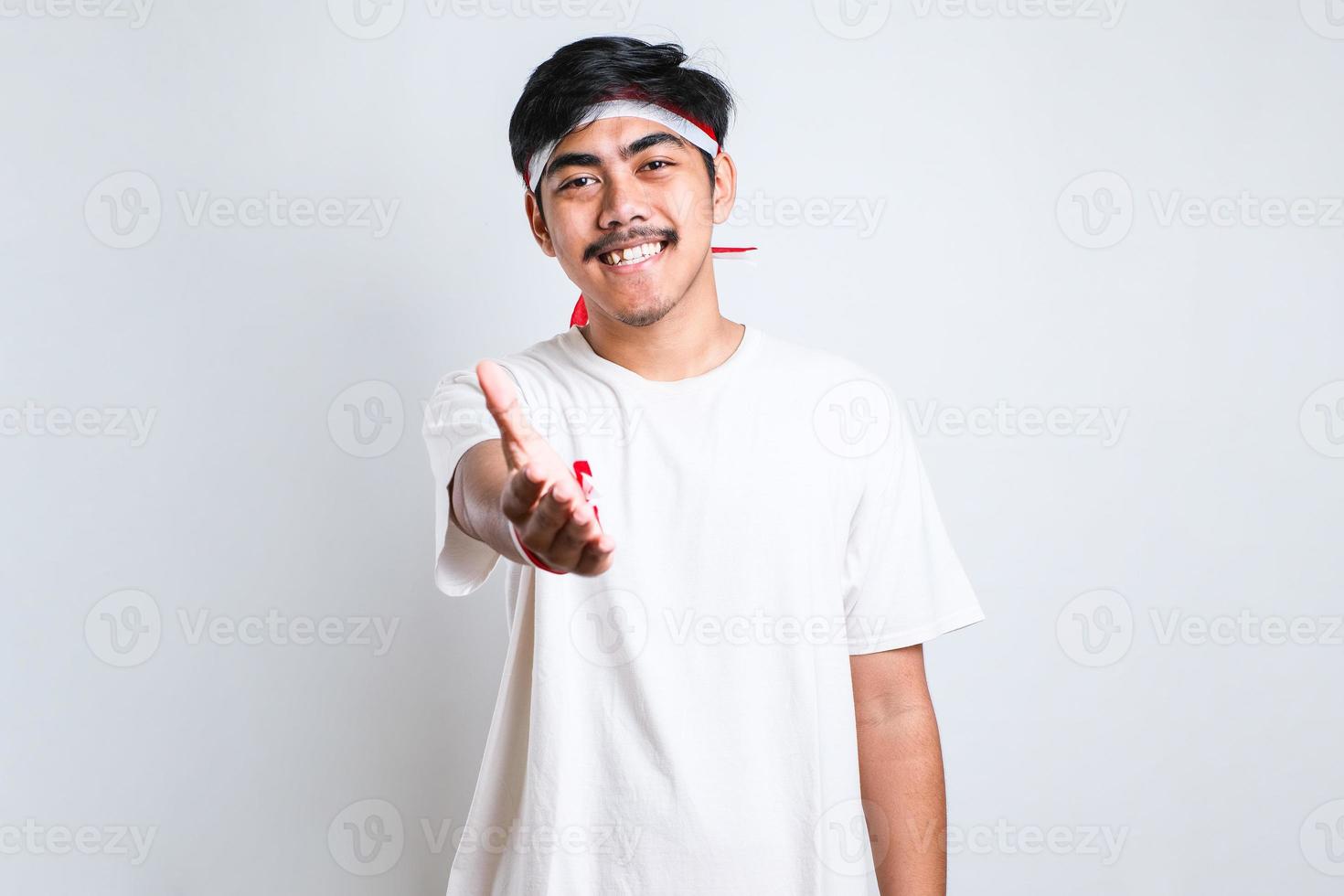 hombre vestido con ropa informal sonriendo amable ofreciendo un apretón de manos como saludo foto