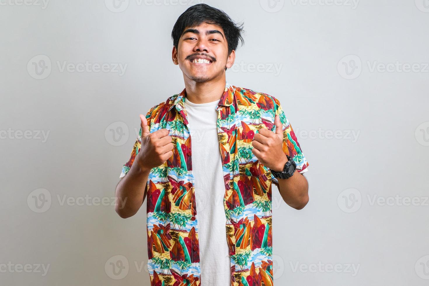 Asian man doing thumbs up smiling and happy for success. Winner gesture. photo