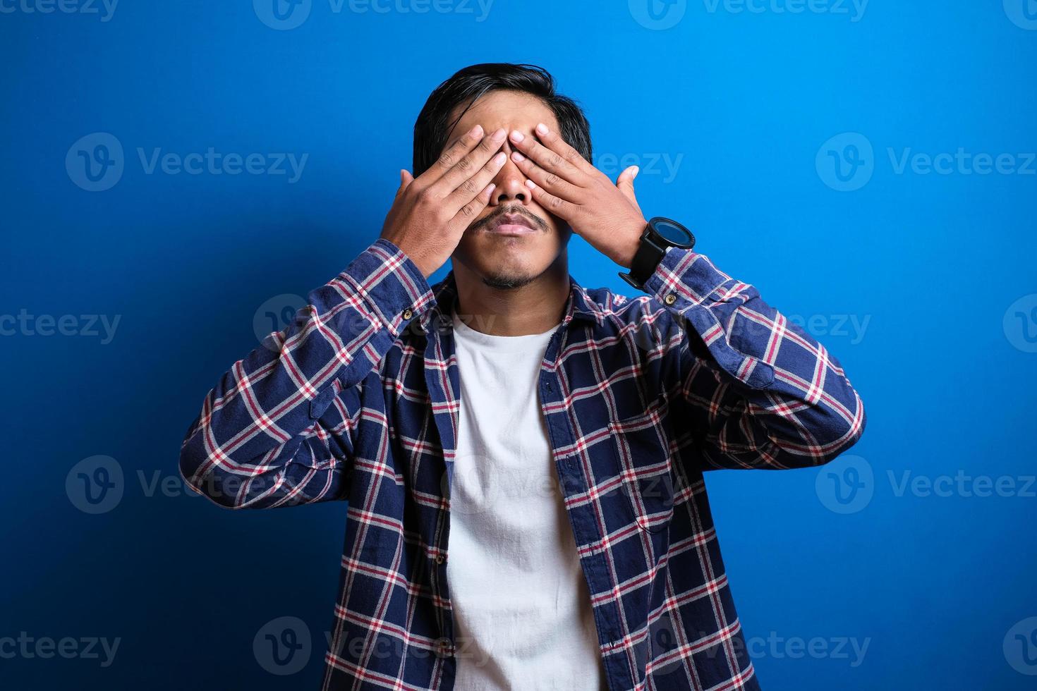 Happy asian man smiles looked at camera against blue background photo