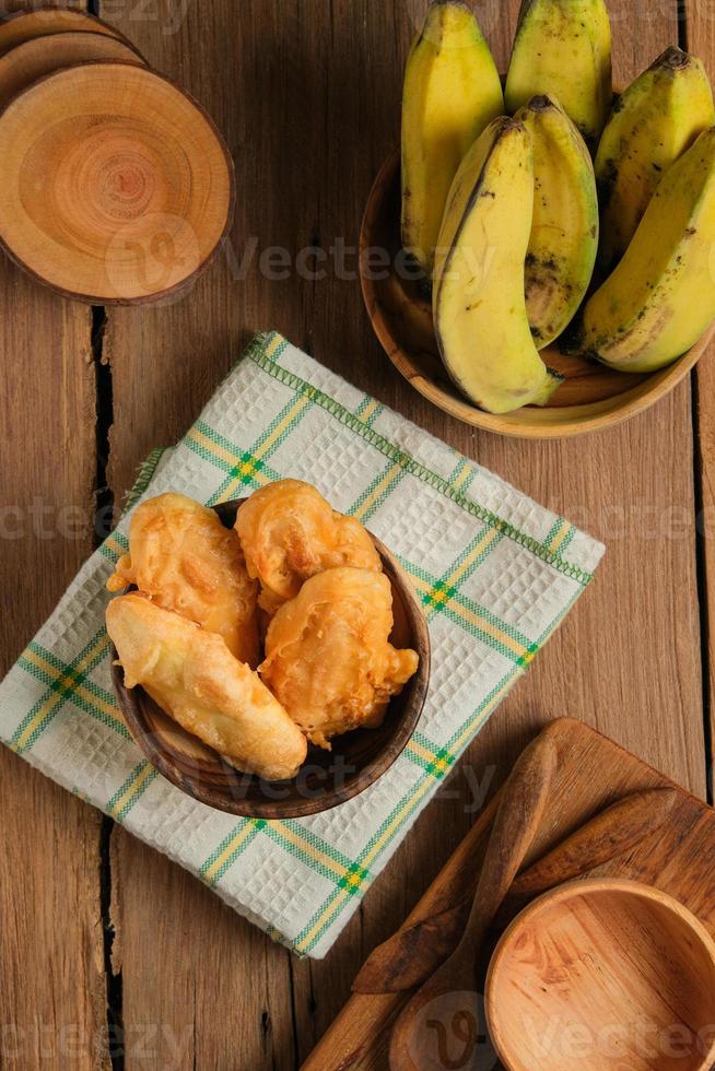 Pisang goreng o plátano frito servido en mesa de madera foto