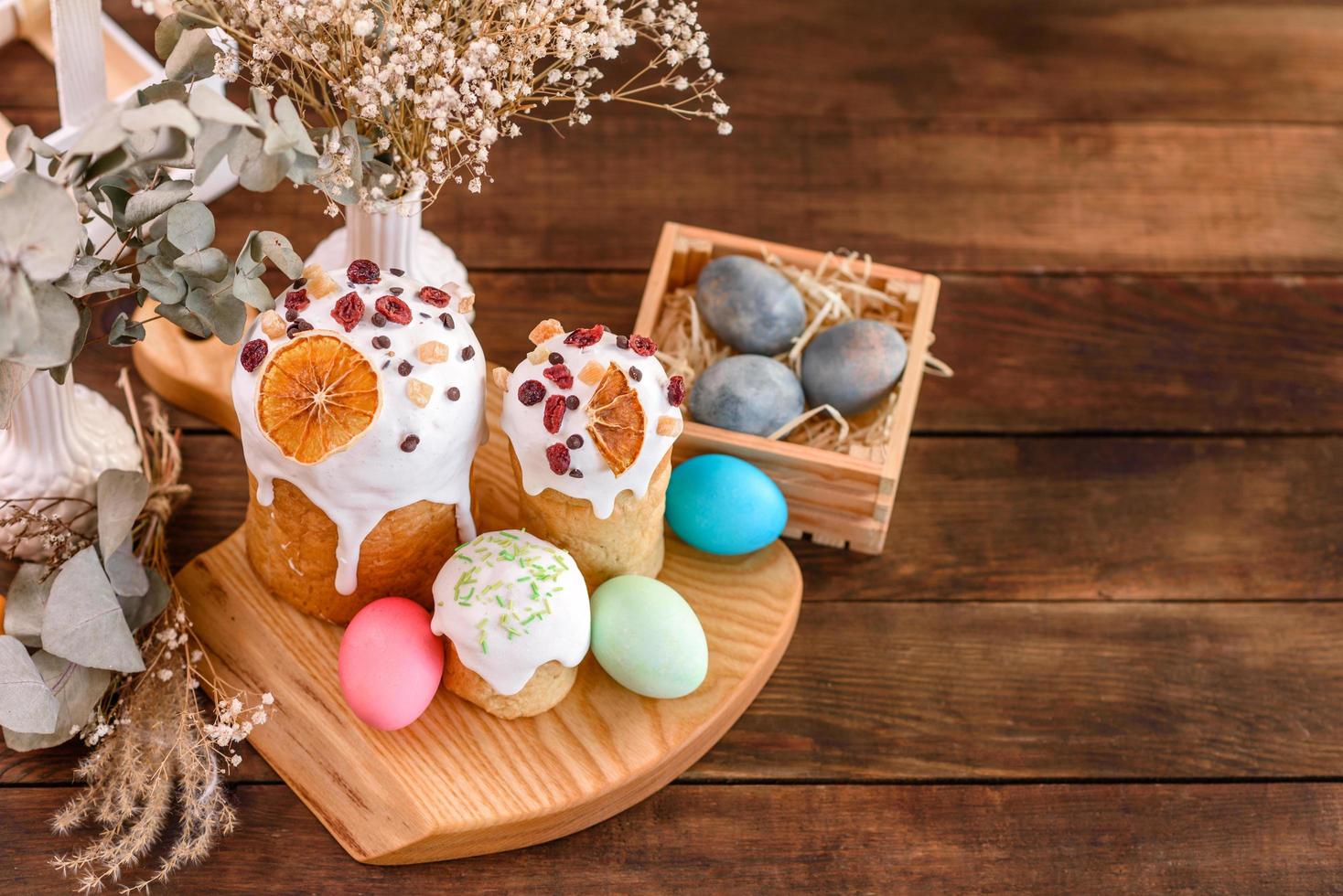 Festive cakes with white glaze, nuts and raisins with Easter eggs on the festive table photo