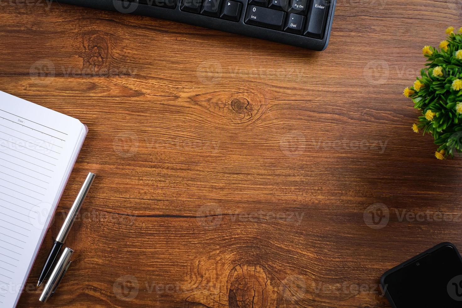 Wooden table with notebook, magnifying glass, pen, decorative plants photo