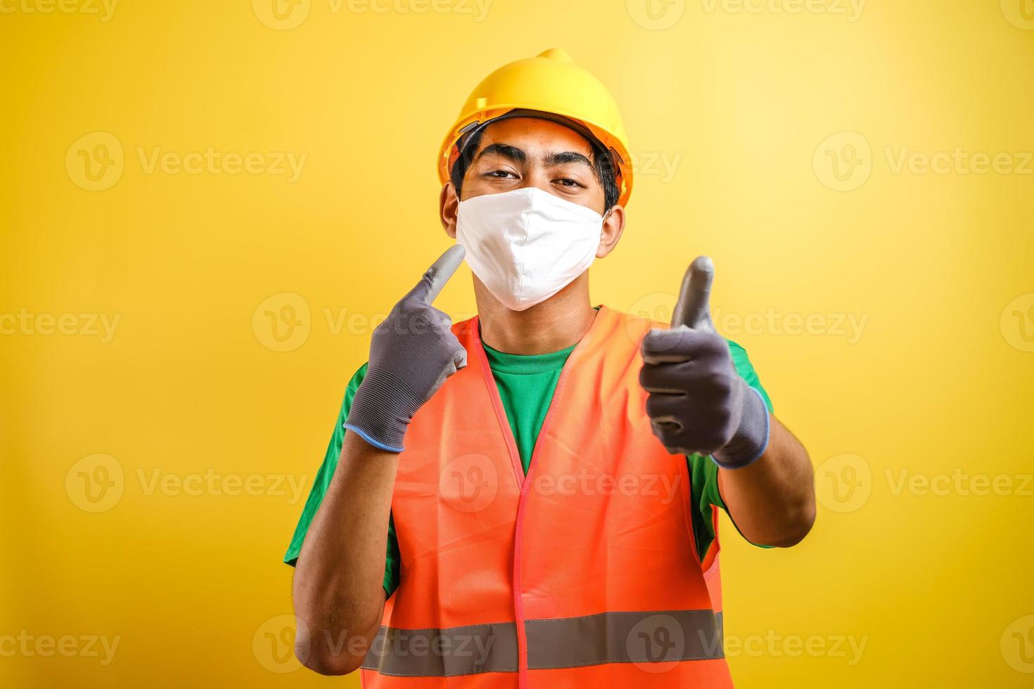 Asian construction worker pointing at his protective mask and savety helmet photo