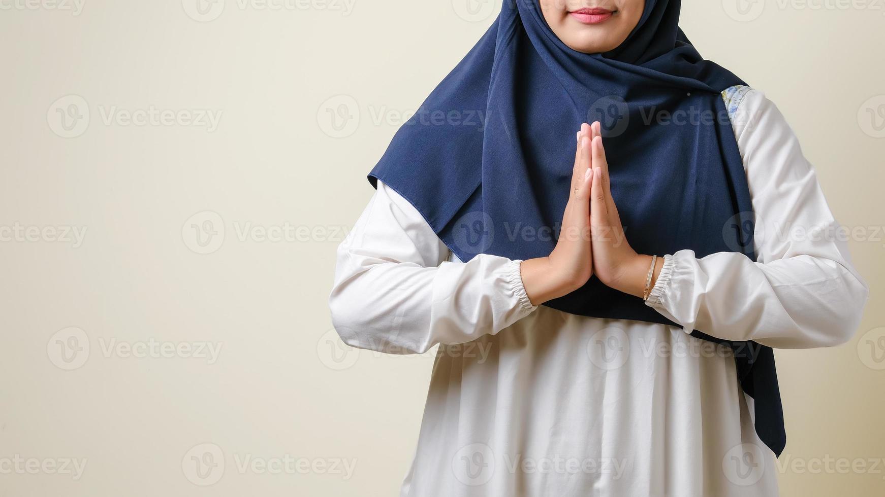 Asian Muslim women wearing hijab gesturing to welcome guests photo