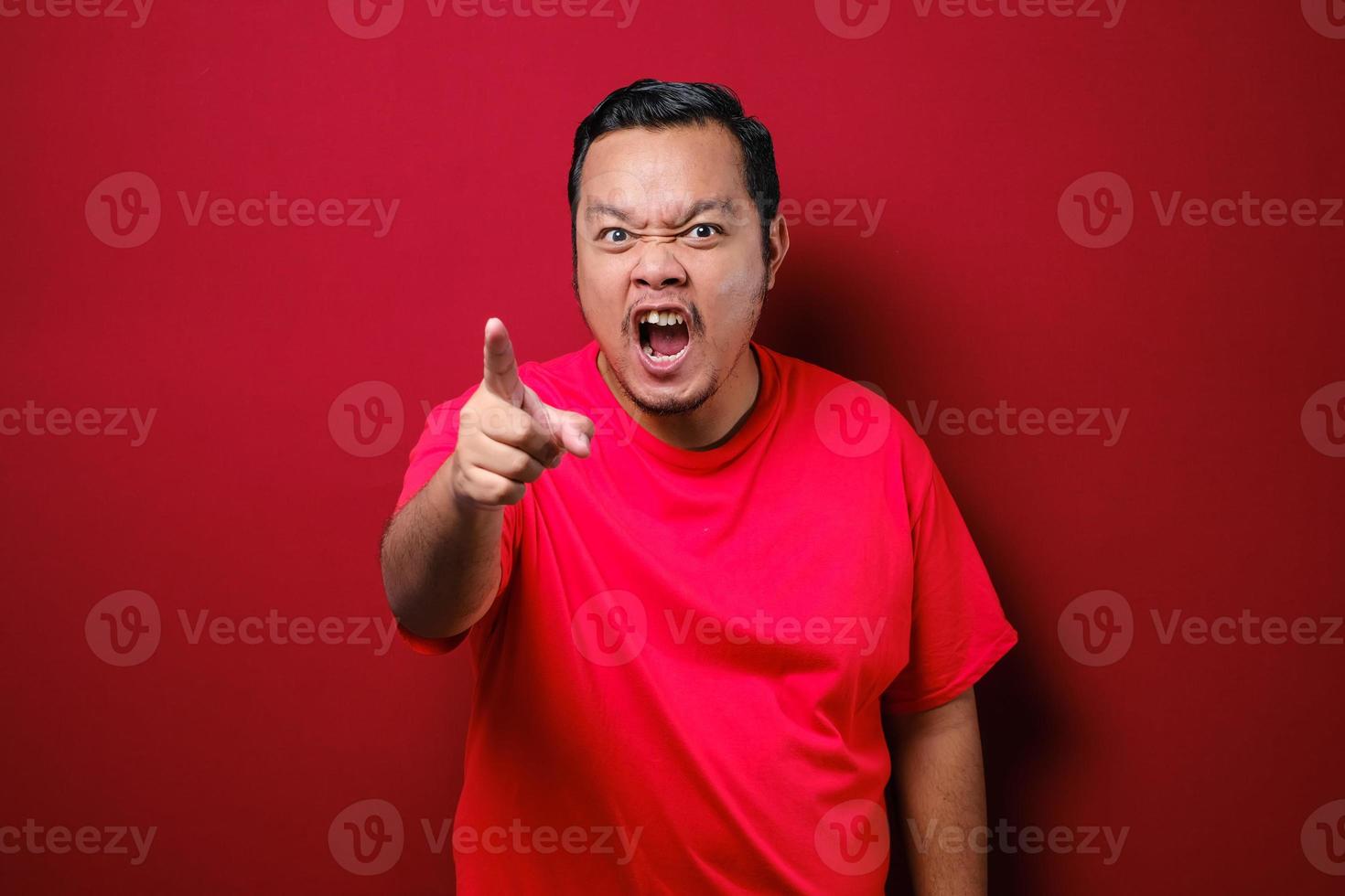 Photo image of funny Asian man showing cynical unhappy angry facial expression pointing forward giving warn