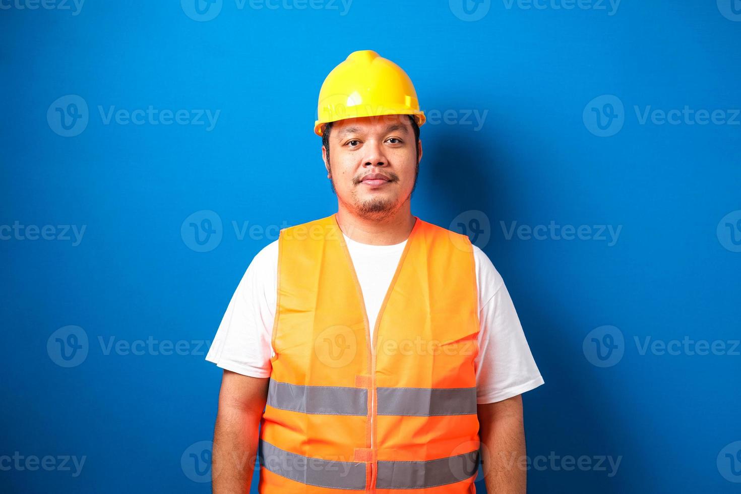 Asian guy wearing helmet and savety vest smiles at the camera photo