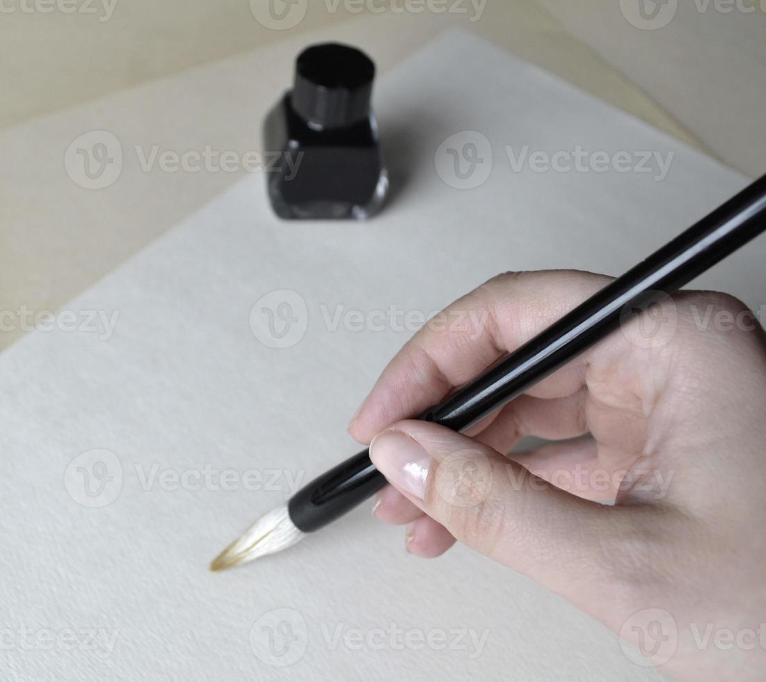 ink bottle with brush in hand for drawing chinese painting on white photo